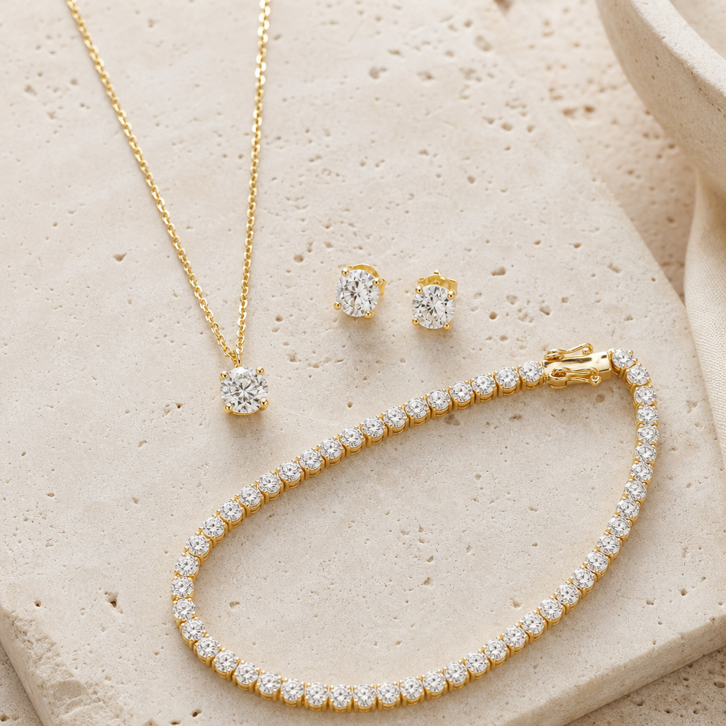 Collana con pendente di diamante, orecchini punto luce e bracciale tennis in oro giallo su travertino chiaro