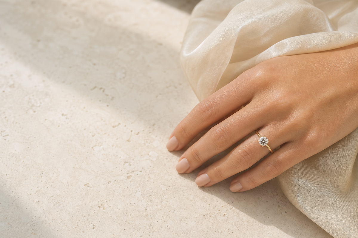Anello solitario in oro giallo con diamante brillante, su una superficie in travertino chiaro